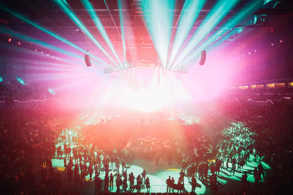 Excited arena audience illuminated by stage lights during an esports event